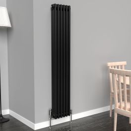 A 1500mm x 290mm Vertical 3-Column Radiator in a Space Black finish with chrome valves within a living room setting.