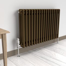 A 500mm x 785mm Horizontal 3-Column radiator in an Antique Brass finish with chrome valves within a living room setting.
