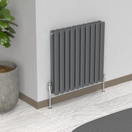 A 600mm x 540mm Horizontal Oval Double Radiator in an Anthracite finish with chrome valves within a living room setting.
