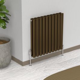 A 600mm x 540mm Horizontal Oval Double Radiator in an Antique Brass finish with chrome valves within a living room setting.

