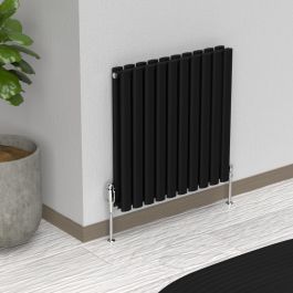 A 600mm x 540mm Horizontal Oval Double Radiator in a Space Black finish with chrome valves within a living room setting.
